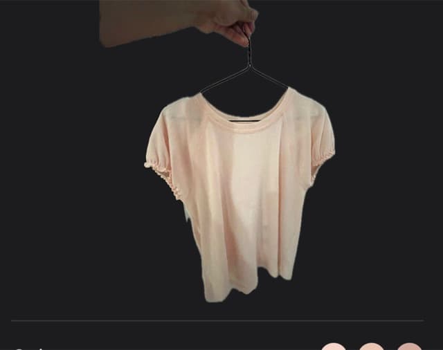 Original pale shirt photographed on a hanger against a dark background